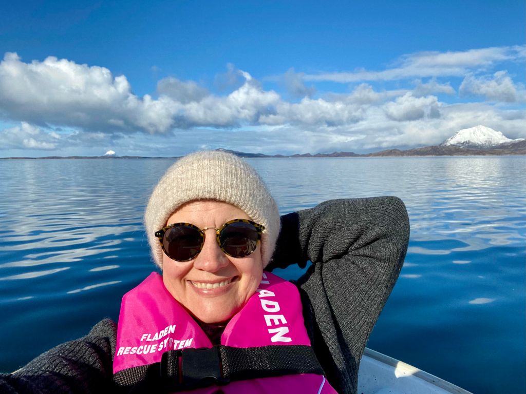 Hobbyfotograf Rigmor Nygård Hansen ute i båt. Lurøyfjellet i bakgrunnen.